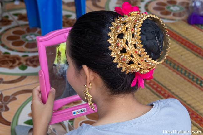 woman looking at her makeup in a mirror