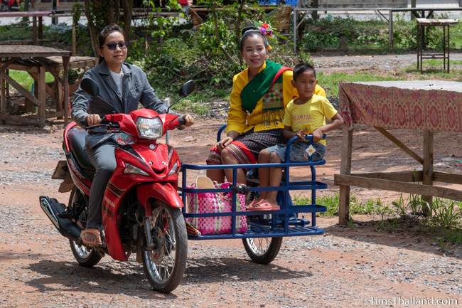 woman in traditional Thai dress riding in a motorcycle sidecar