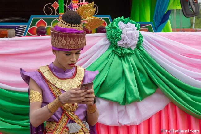 boy in traditional Thai dress on his phone