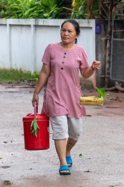 woman carrying kratong and water bucket