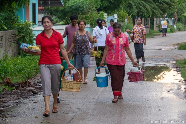 women carrying kratong, food baskets, and water buckets
