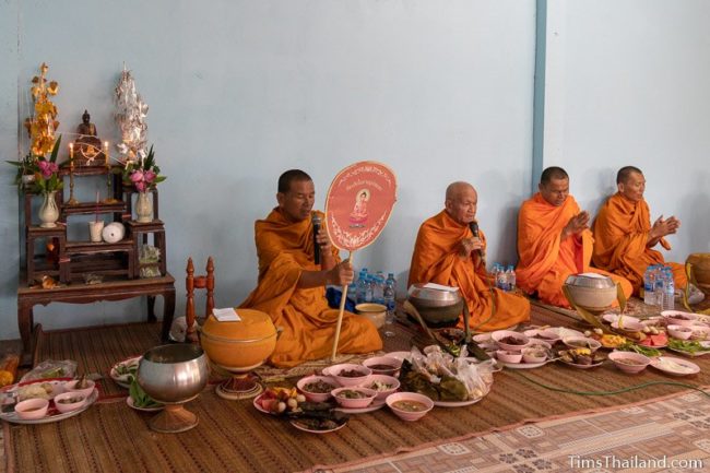 monks chanting with trays of food in front of them