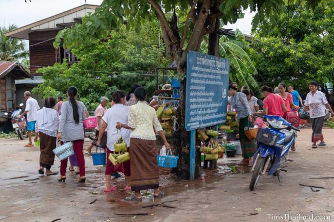 women walking home with kratong and water buckets after ceremony