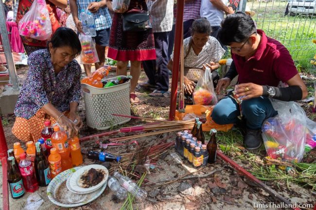 putting drink offerings on ground under shrine