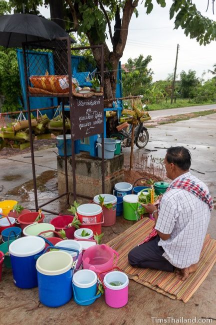 man holding candles and leaves in front of shrine