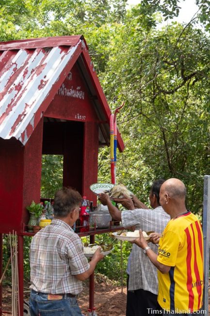 men putting food on a shrine