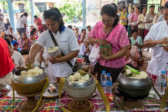people putting food in monk alms bowls