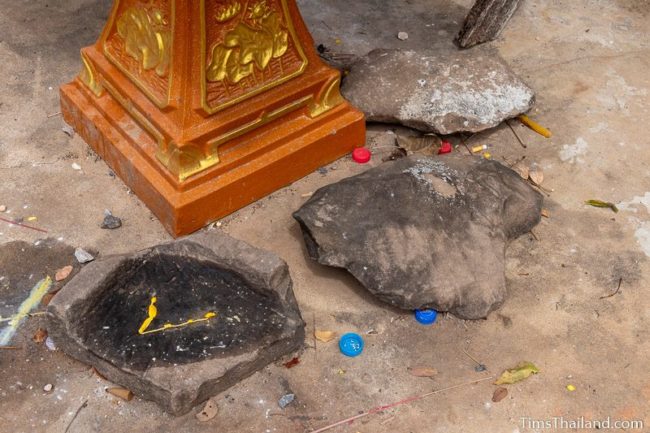 three pieces of sandstone on ground in front of village shrine