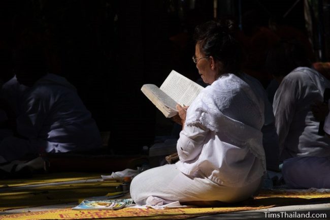 woman in white reading a chanting book