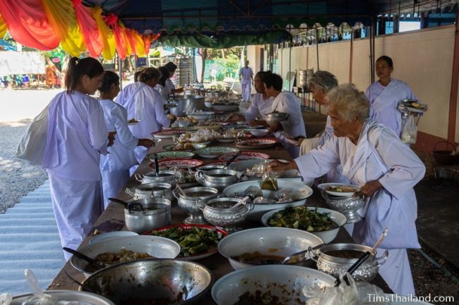 women wearing white taking food off a table