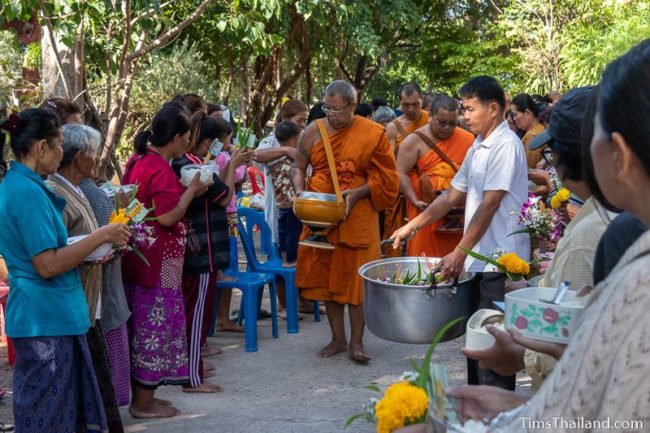 monks collecting alms from a line of people