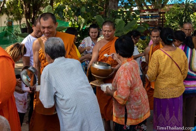 monks collecting alms from a line of people