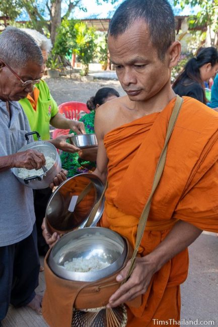 monk collecting alms from a line of people