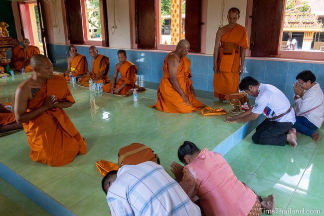 parents bowing down before men about to become monks