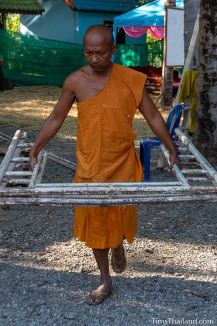 monk carrying a piece of scaffolding