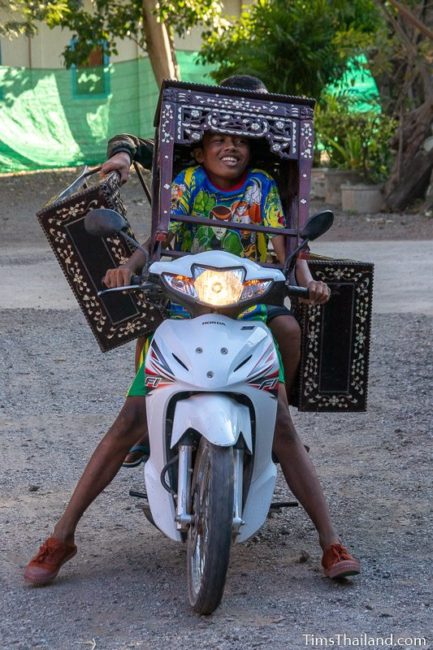 boys on motorcycle carrying three small tables