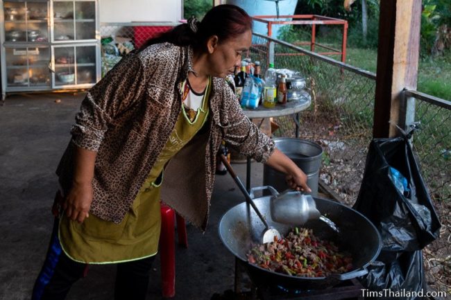 woman pouring water into a giant wok