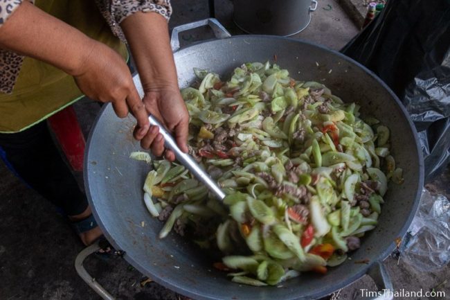 woman stirring food in a giat wok