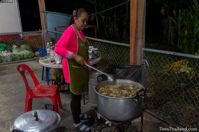 woman stirring food in a giant pan