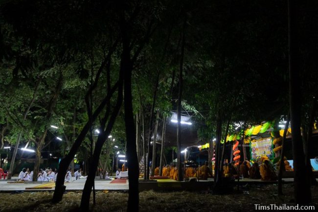 monks and people in white chanting during the night