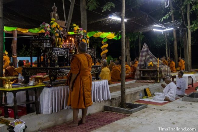 monk lighting candles in front of a Buddha image