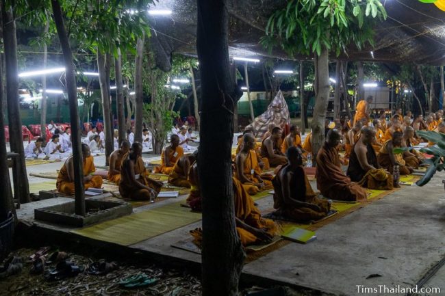 monks and people in white chanting during the night