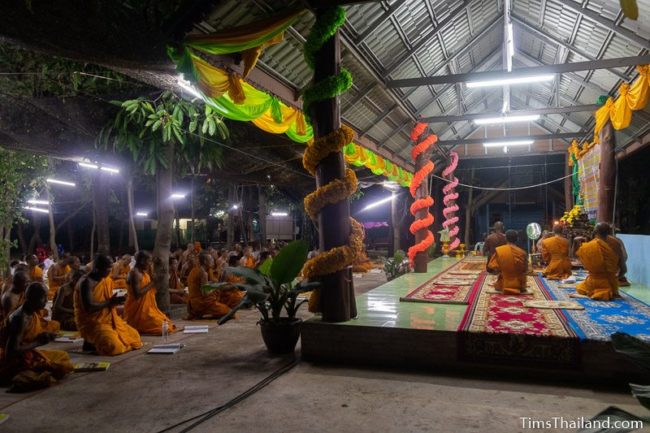 monks and people in white chanting during the night