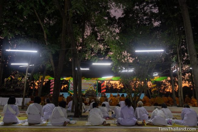 monks and people in white chanting during the night