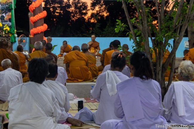 monks and people in white chanting during the night