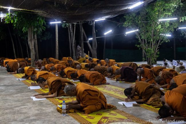 monks and people in white chanting during the night