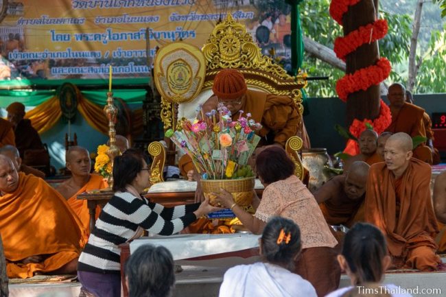 people giving a monkey tree to a monk