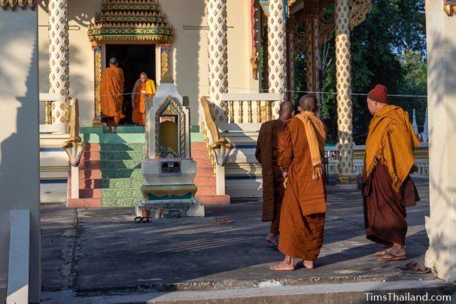 two monks walking in and out of ubosot