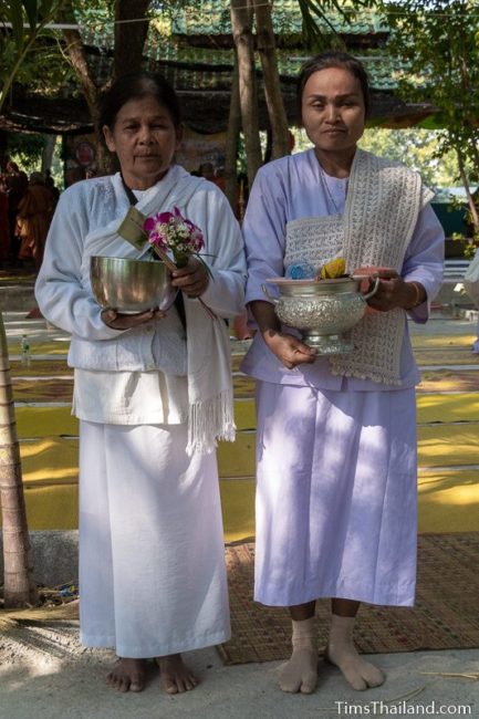 two women in white holding flowers