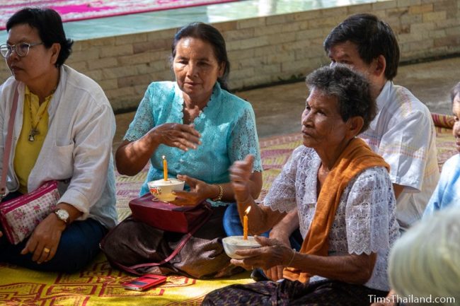 women holding candles in ceremony for men who will become monks