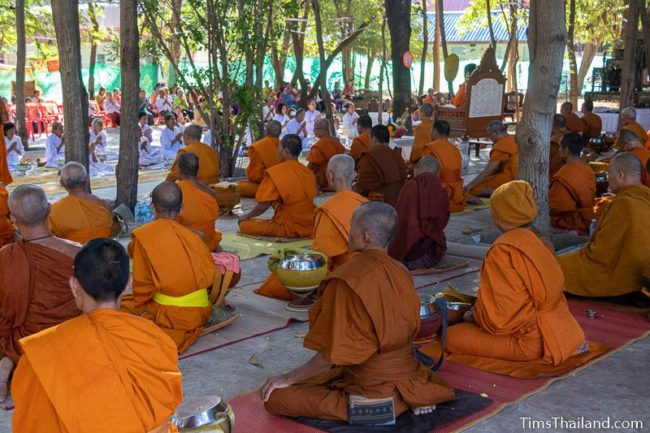 monks and people in white listening to a sermon