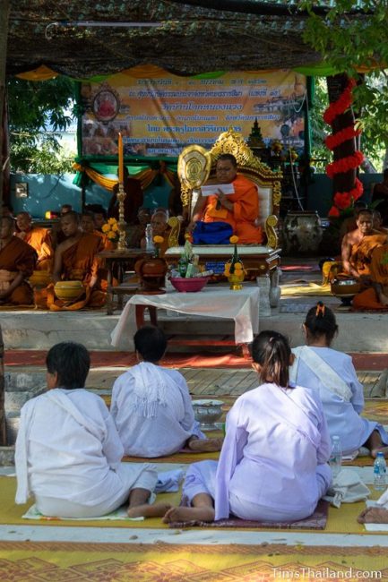 monks and people in white listening to a sermon