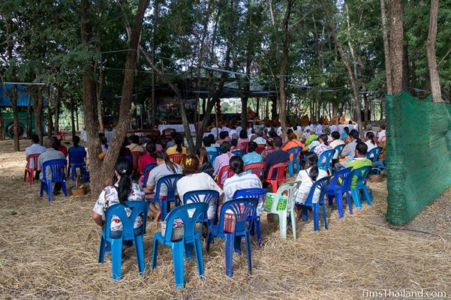 monks, people in white, and lay people listening to a sermon