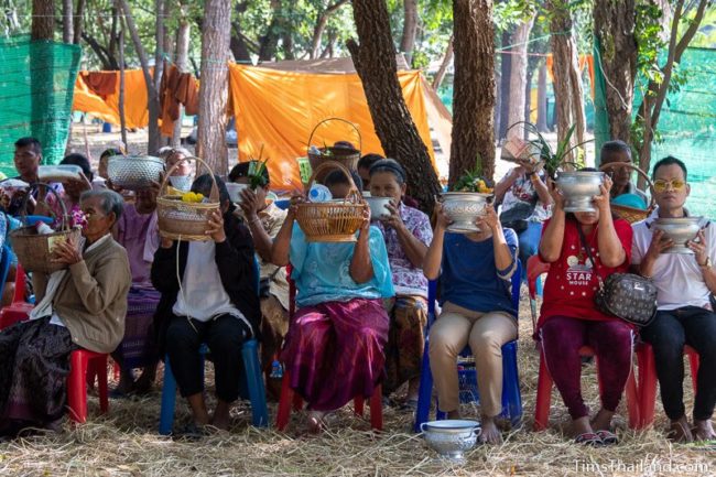 people holding up rice baskets for getting a blessing