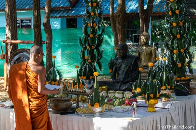 monk leading ceremony in front of monk statue