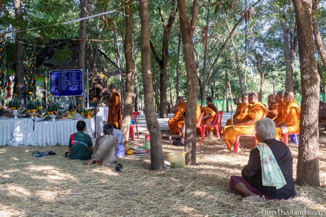 monk leading ceremony in front of monk statue