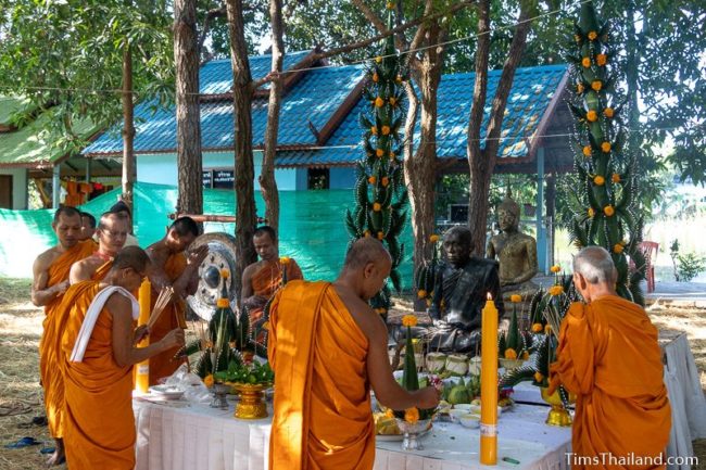 monks lighting incense around monk statue