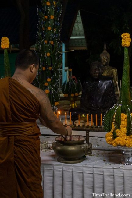 people lighting incense in front of a monk statue