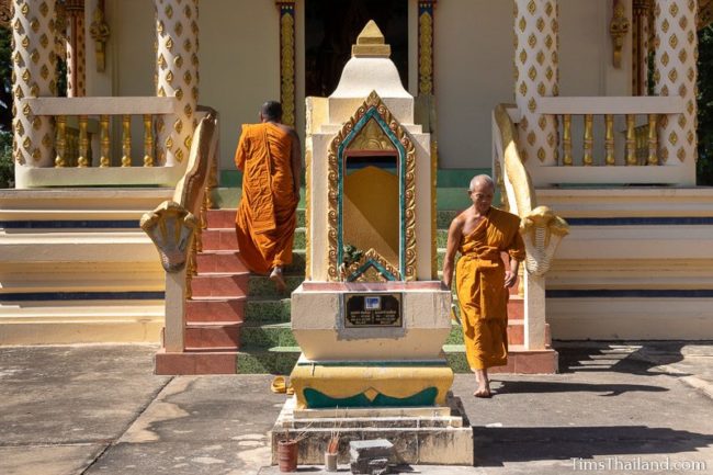 two monks walking in and out of ubosot