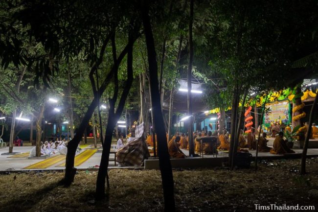 monks and people in white chanting during the night