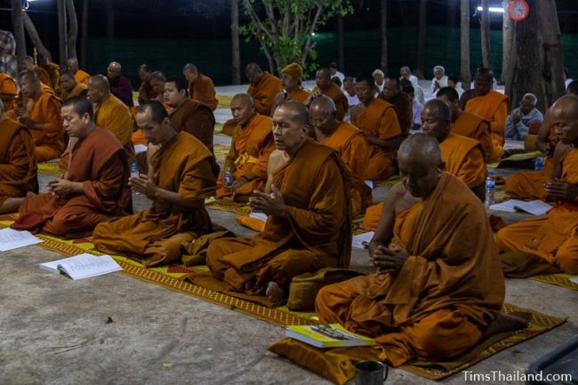 monks and people in white chanting during the night