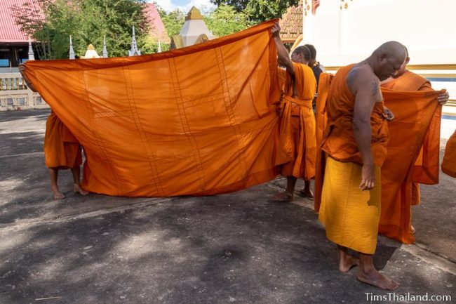 monks helping men ordaining to be monks put on their robes