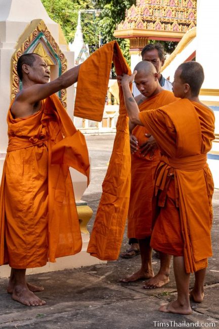 monks helping a man ordaining to be a monk put on his robes