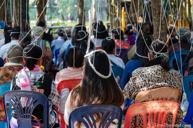 people sitting with white strings tied above them