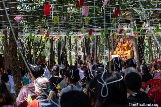 people sitting with white strings tied above them