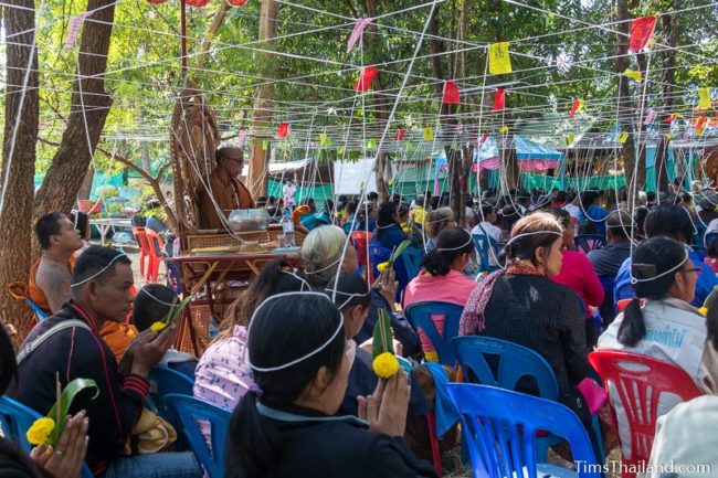 people sitting with white strings tied above them